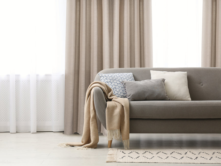Carrera jacquard light filtering grommet curtain in beige, styled at a window