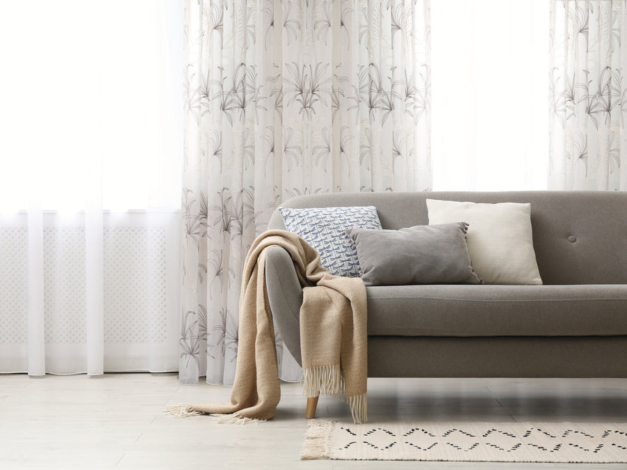 Fiji embroidered floral sheer grommet curtain in beige grey, styled at a window