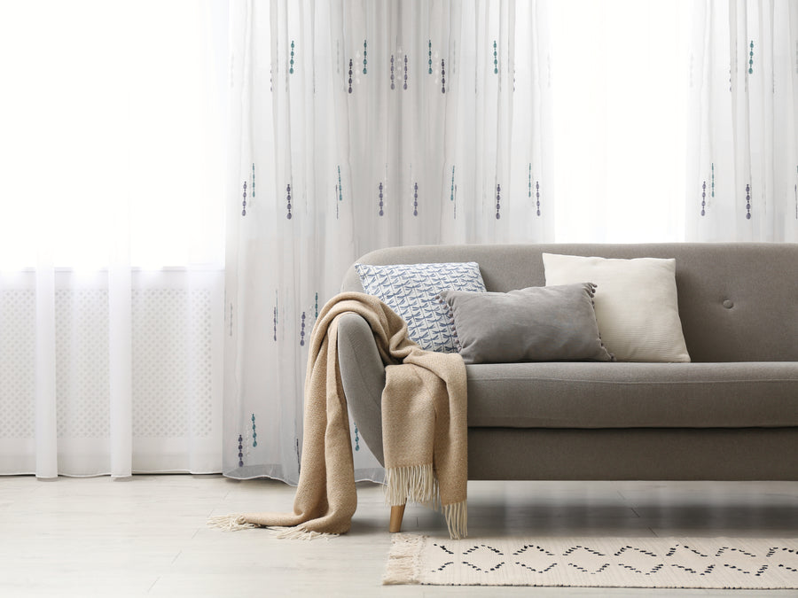 Lodi subtle embroidered sheer grommet curtain in teal, styled at a window